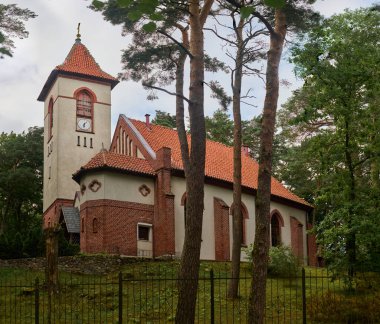 Svetlogorsk, Rusya - 13.07.2024 - St. Seraphim Sarovskiy 'in büyüleyici tuğla kilisesi yemyeşil ormanlarda yuva yapmış, uzun çamlar ve büyüleyici saat kulesi