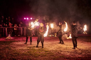 Kaliningrad, Rusya - 10.09.2022 - Muhteşem gece gösterisinde ateş poi ile dans eden sanatçılar, gece gökyüzü altında ateşli hareketler, izleyiciler