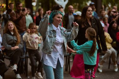Kaliningrad, Rusya - 11.08.2024 - enerjik genç ve yetişkin dişiler canlı danslardan hoşlanırlar. Parktaki ağaçların arasından gün ışığı filtreleri, kalabalığa canlı bir zemin ekliyor