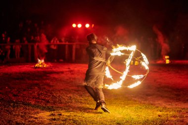 Kaliningrad, Rusya - 10.09.2022 - Muhteşem gece gösterisinde ateş topuyla dans eden sanatçı, gece gökyüzü altında ateşli hareketler, izleyiciler