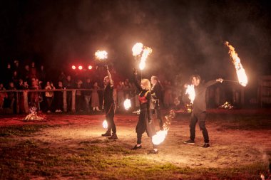 Kaliningrad, Rusya - 10.09.2022 - Muhteşem gece gösterisinde ateş poi ile dans eden sanatçılar, gece gökyüzü altında ateşli hareketler, izleyiciler