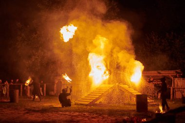 Kaliningrad, Rusya - 10.09.2022 - Gece gökyüzünde ışıl ışıl yanan ateş personeli silueti, bir açık hava yangın gösterisi sırasında enerji ve ateş manipülasyonu sanatını sergiliyor