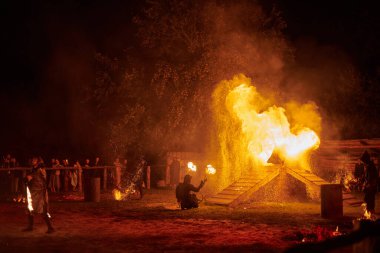 Kaliningrad, Rusya - 10.09.2022 - Gece gökyüzünde ışıl ışıl yanan ateş personeli silueti, bir açık hava yangın gösterisi sırasında enerji ve ateş manipülasyonu sanatını sergiliyor