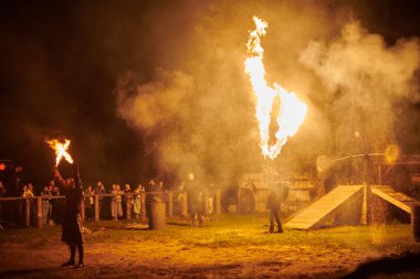 Kaliningrad, Rusya - 10.09.2022 - Çift alev fırlatıcı sanatçılar gece gökyüzüne muazzam alev akıntıları salıyor, ateş ustalığını ve ateş performansını temsil ediyor