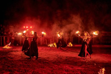 Kaliningrad, Rusya - 10.09.2022 - Muhteşem gece gösterisinde otantik bir elbiseyle dans eden ateş gösterisi sanatçıları, gece gökyüzü altında ateşli hareketler, izleyiciler