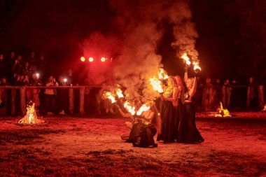 Kaliningrad, Rusya - 10.09.2022 - Muhteşem gece gösterisinde otantik bir elbiseyle dans eden ateş gösterisi sanatçıları, gece gökyüzü altında ateşli hareketler, izleyiciler