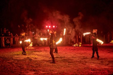 Kaliningrad, Rusya - 10.09.2022 - Muhteşem gece gösterisinde ateş poi ile dans eden sanatçılar, gece gökyüzü altında ateşli hareketler, izleyiciler
