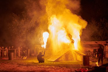 Kaliningrad, Rusya - 10.09.2022 - Gece gökyüzünde ışıl ışıl yanan ateş personeli silueti, bir açık hava yangın gösterisi sırasında enerji ve ateş manipülasyonu sanatını sergiliyor