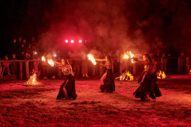 Kaliningrad, Rusya - 10.09.2022 - Muhteşem gece gösterisinde otantik bir elbiseyle dans eden ateş gösterisi sanatçıları, gece gökyüzü altında ateşli hareketler, izleyiciler
