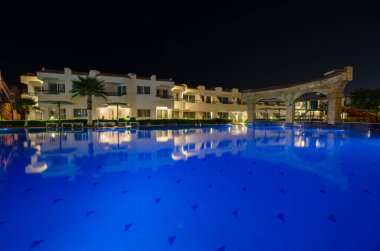 Sakin otel ortamları, açık gece gökyüzü altında masmavi renkleri yansıtan havuz ışıkları. Akdeniz mimarisi ortamın sakinleştirilmesini, tatil beldelerinin çevre parlaklığıyla geliştirilmesini tamamlıyor