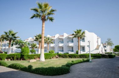 Çağdaş tatil beldesinde beyaz mimari, bereketli yeşillik ve uzun palmiye ağaçları bulunur. Parlak güneş ışığı huzurlu atmosferi güçlendirir. Kıtır mavi gökyüzü mükemmel bir zemin oluşturur