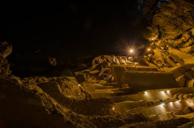 Cliffside Resort geceleri sıcak ışıklarla aydınlatılıyor. Yükseltilmiş perspektif terasları ve çevreleyen engebeli manzaraları gösteriyor. Karanlık gökyüzü karşıt altın renkler