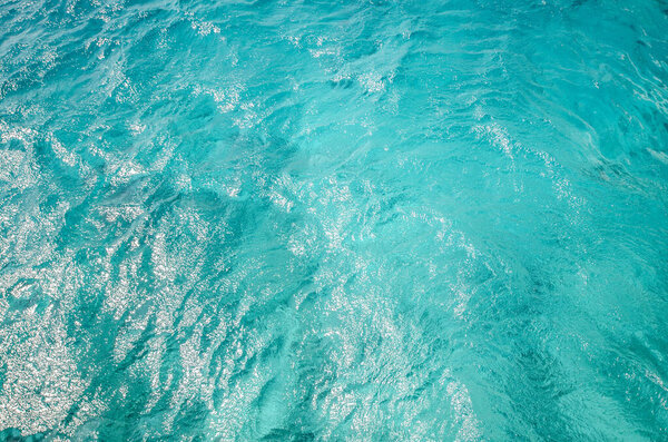 Vivid turquoise waters of Red Sea shimmer under sunlight. Aerial perspective reveals texture and movement. Bright, serene colors highlight ocean tranquility