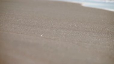 Yumuşak sabah ışığı sakin kıyı şeridinde hafif dalgalar üzerinde dans eder. Işıldayan yansımalar sakin plajda sakinleştirici, ışıl ışıl bir etki yaratır. Sıcak tonlar erken saatleri ve huzurlu ortamı vurguluyor