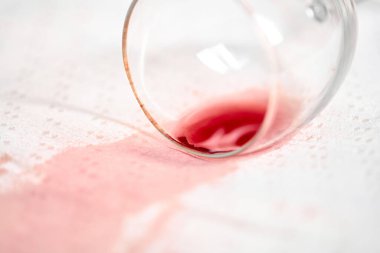 Boş şarap kadehi yan yatar ve kırmızı sıvıyı gevrek beyaz masa örtüsüne döker. Olay yeri kazara dökülme anını yakalıyor, katıksız renk kontrastını ve tesadüfi atmosferi vurguluyor