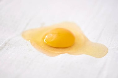 Parlak sarı yumurta sarısı dokulu beyaz yüzeye dayanır. Yumuşak ışıklandırma sarısı sarısı parlak dokuyu, emici arkaplanla çelişir. Yakın çekim aşçılık basitliğini yakalar