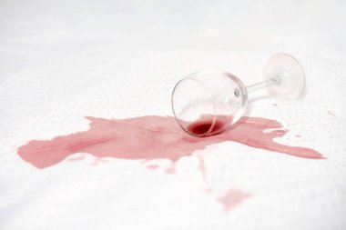 Beyaz kumaş üzerine düşen cam zengin kırmızı bir leke yaratır. Derin sızıntı ve parlak arka plan arasındaki zıtlık. Sahne kazara ama dinamik bir aksilik taşıyor