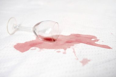 Beyaz kumaş üzerine düşen cam zengin kırmızı bir leke yaratır. Derin sızıntı ve parlak arka plan arasındaki zıtlık. Sahne kazara ama dinamik bir aksilik taşıyor