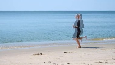 Genç sarışın kadın Baltık Denizi sahilinde koşuyor, dinamik hareket izleri yaratıyor. Parlak, güneşli bir gün, dingin okyanus geçmişini ve kumlu önplanı geliştirir. Enerjik ve özgür ruhlu sahne