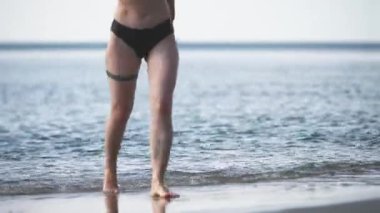 Sıcak yaz gününde çekilen huzurlu baltık sahnesi. Yumuşak dalgalar, yumuşak ve dağınık ışığın altında kumlu sahille buluşur. Tanımlanamayan kişi ön planda duruyor ve derinlik ekliyor