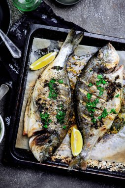 Kızarmış dorado, bir tepside otlar ve fırında patatesler. Üst vei. Seçici bir odak noktası.