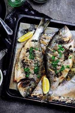 Kızarmış dorado, bir tepside otlar ve fırında patatesler. Üst vei. Seçici bir odak noktası.