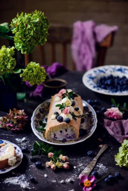 Sünger rulo yaban mersinli ve kremalı bir masa seti... klasik tarzda. Seçici odaklanma.