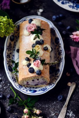 Sünger rulo yaban mersinli ve kremalı bir masa seti... klasik tarzda. Seçici odaklanma.