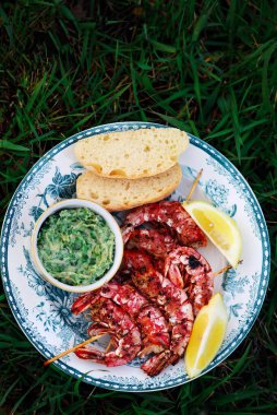 Bahçedeki ızgarada bitkisel sarımsaklı tereyağlı ızgara karides.