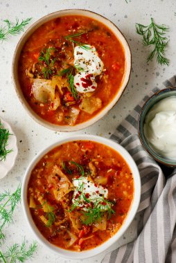 Masadaki seramik kasede lahana rulosu çorbası. Üstte veiw.style sarılma. Seçici odak