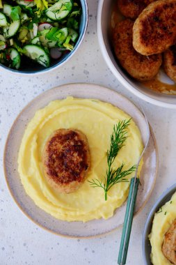 Patates püresi ve taze sebze salatasıyla tabakta tavuk pirzolası.