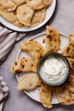 Ekşi kremalı ördek ve tabakta kızarmış soğanlı Pierogi. seçici odak