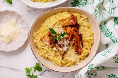 Kurabiyeli Orzotto, parmesan peyniri ve maydanozlu, seramik kasede seçici bir odak noktası.