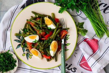 Yeşil fasülyeli sıcak sebze salatası ve bir tabakta kaynamış yumurta.