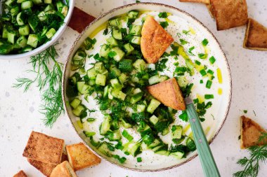 Salatalık, dereotu ve yeşil soğan salatasıyla çırpılmış feta ve kızarmış pide parçaları. Seçici odaklanma. Üst veiw