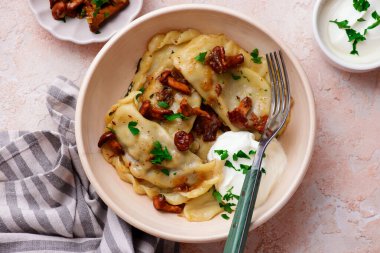 Kızarmış mantarlı Polonya hamur tatlısı ve bir tabakta ekşi krema. seçici odak