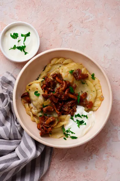 stock image Polish dumplings with fried chanterelles and sour cream on a plate .top veiw. selective focus