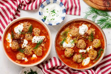 Romanian Cabbage Soup with Meatballs, Tomatoes and Sour Cream in a ceramic bowl on a table. top veiw.style hugge.selective focus clipart