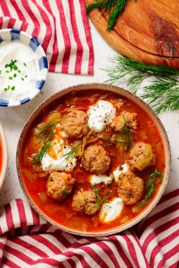 Romanian Cabbage Soup with Meatballs, Tomatoes and Sour Cream in a ceramic bowl on a table. top veiw.style hugge.selective focus clipart