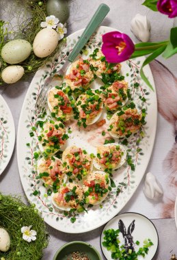 Paskalya arka planında domuz pastırması ve yeşil soğanla doldurulmuş yumurtalar.