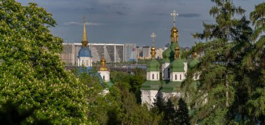 Kyiv 'deki Vydubychi Manastırı' nın manzarası altın kubbeler ve yeşil çatılar, Dinyeper 'lerin modern siluetine karşı kurulmuştur..
