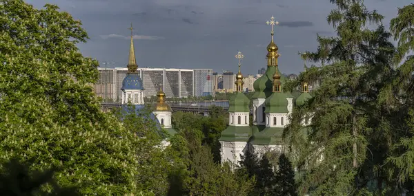 Kyiv 'deki Vydubychi Manastırı' nın manzarası altın kubbeler ve yeşil çatılar, Dinyeper 'lerin modern siluetine karşı kurulmuştur..