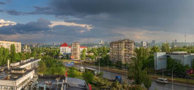  Yağmur sonrası Kyiv 'in panoramik manzarası dramatik bulutlar, ıslak yollar, Sovyet tarzı binalar ve akşam güneşinin altında parlayan yemyeşil alanlar..