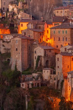 İtalya 'nın Toskana kentindeki bir tepe köyü olan Sorano' nun ortaçağ taş evlerinde sıcak akşam ışığı parlıyor. Tarihsel mimari ve dar sokaklar zamansız ve romantik bir atmosfer yaratır..