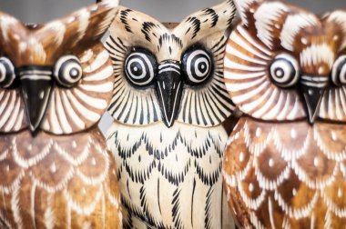 Ahşap baykuşların baş heykellerine yakın plan, gözle görülür ahşap tahıllar oyulmuş..