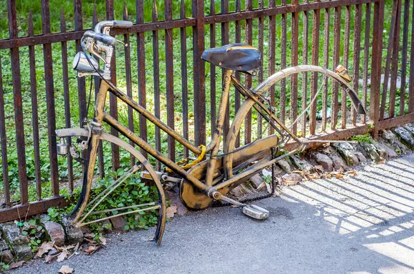 울타리에 부식되고 버려진 자전거가 굴러가고 여정은 멈췄습니다 바퀴는 없어지고 자연은 스톡 사진