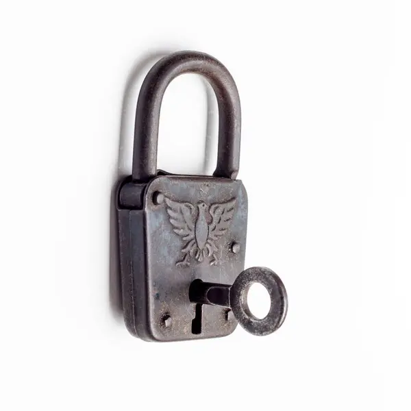 白い背景に隔離されたキーが付いているアンティークなパドロック 老化したチャームによる概念的セキュリティ ストック写真