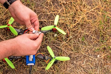 Erkek eller yerdeki DIY İHA üzerinde çalışıyor.