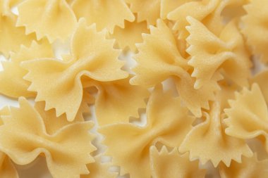 Beyaz arka planda bir yığın İtalyan çiğ Farfalle veya papyon makarna, makro yakın plan.