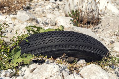 Nehir kıyısındaki taşların arasında gömülü lastik, kirlilik kavramı